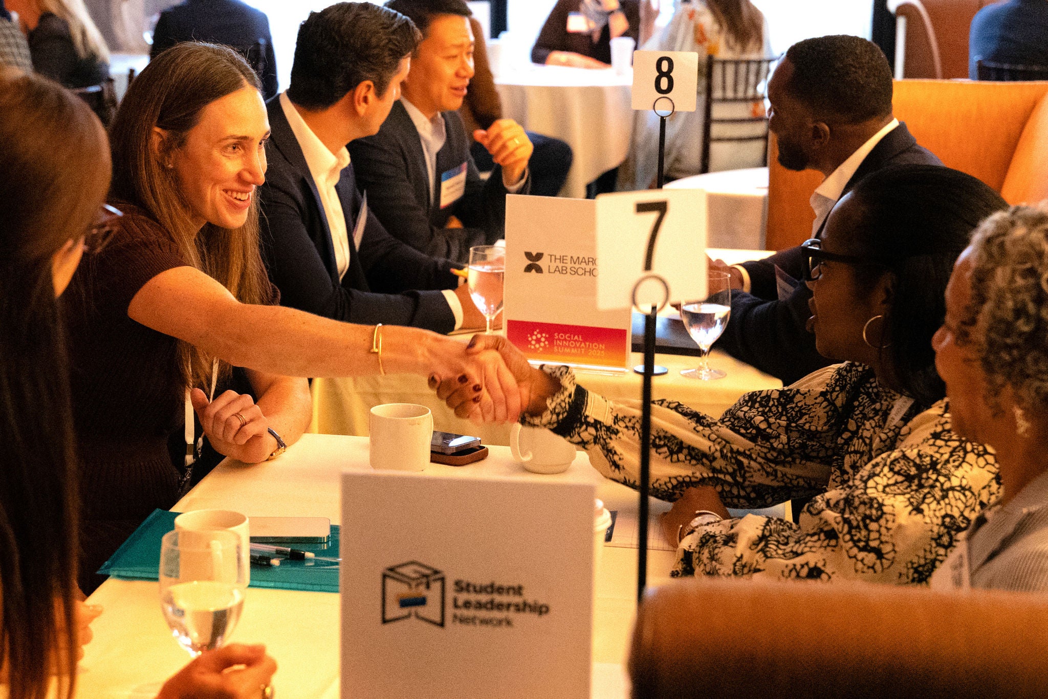 Apollo at Social Innovation Summit 2025 Attendees at the Social Innovation Summit 2025 participate in nonprofit board matchmaking, exchanging handshakes and ideas across tables marked by nonprofit organization signs.