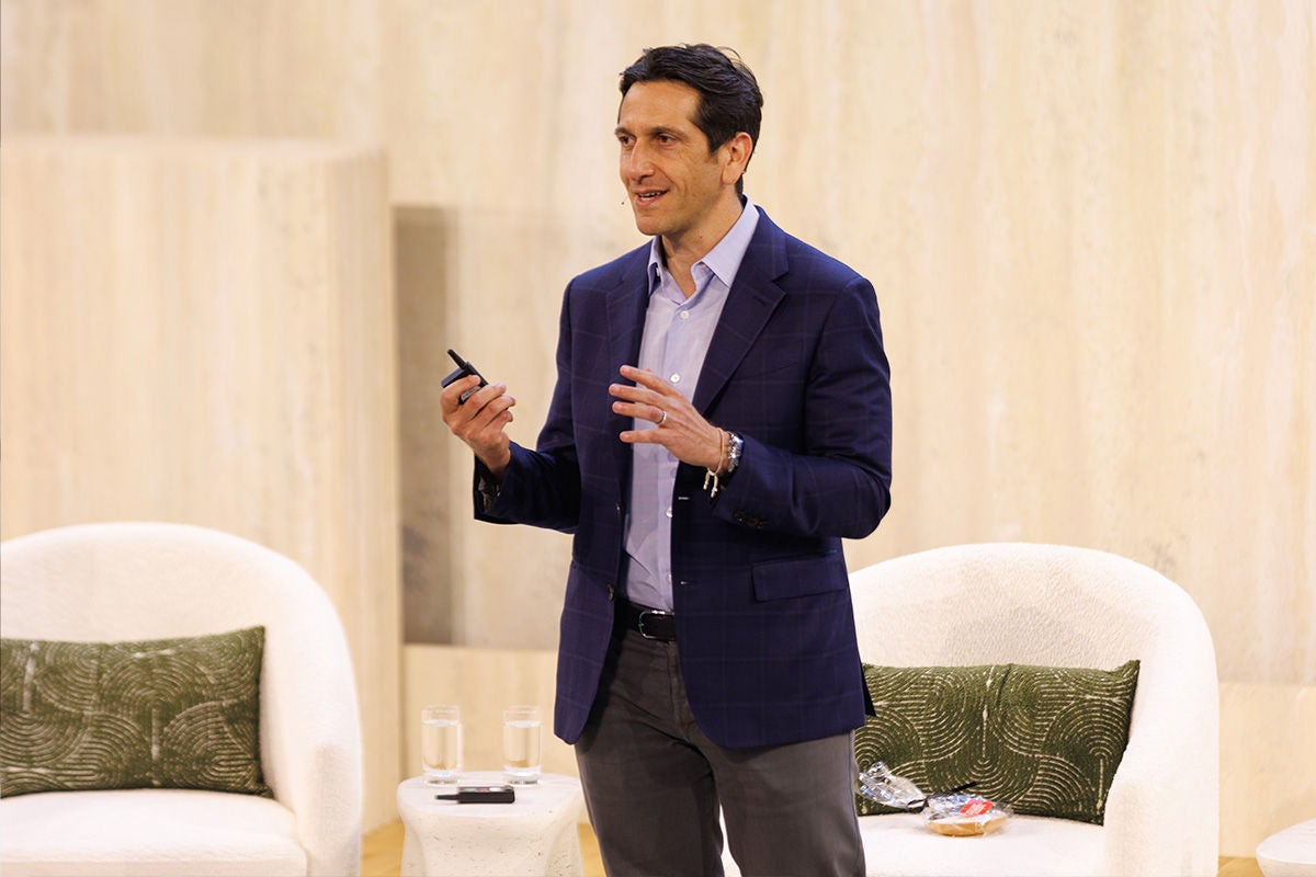 Matt Nord, Apollo Partner and Co-Head of Private Equity and Head of Hybrid, speaking at the 2026 Apollo Hybrid Capital Summit, gesturing while addressing the audience, with white bouclé lounge chairs and a travertine stone backdrop behind him.