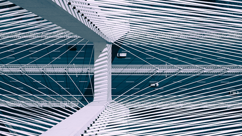 Aerial view of vehicles crossing a modern cable-stayed bridge, representing real assets and infrastructure investments.  