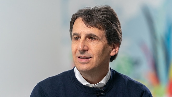 Portrait of a single individual in a dark sweater over a white collared shirt, set against a light, blurred background. Represents Apollo’s leadership in asset management, capital solutions, and alternative investments.