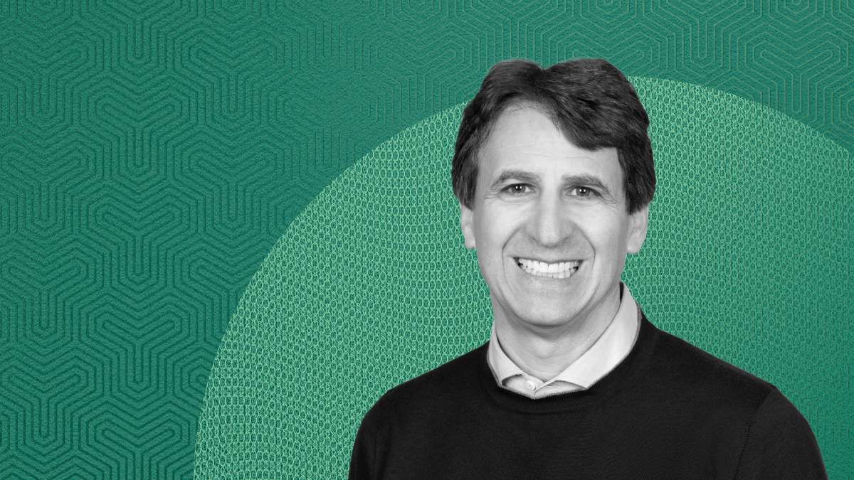 Portrait of Marc Rowan, CEO of Apollo Global Management, smiling in a studio setting with a green patterned background, accompanying an interview on Japan’s economic and investment outlook in global private markets.