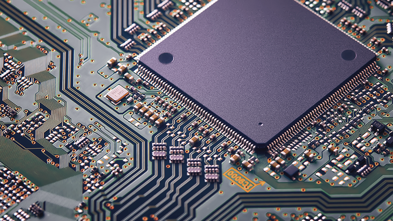 Close-up of a semiconductor microchip on a circuit board, showing pathways, solder points, and components that support software processing and digital infrastructure systems.