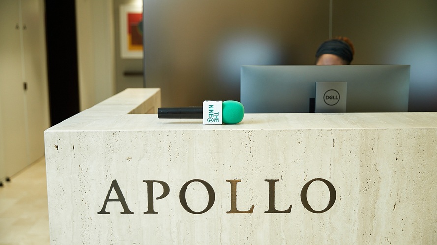 Apollo reception desk featuring the Apollo name on a stone front panel, with a Nine at Nine microphone resting on the counter and a staff member seated behind a computer.